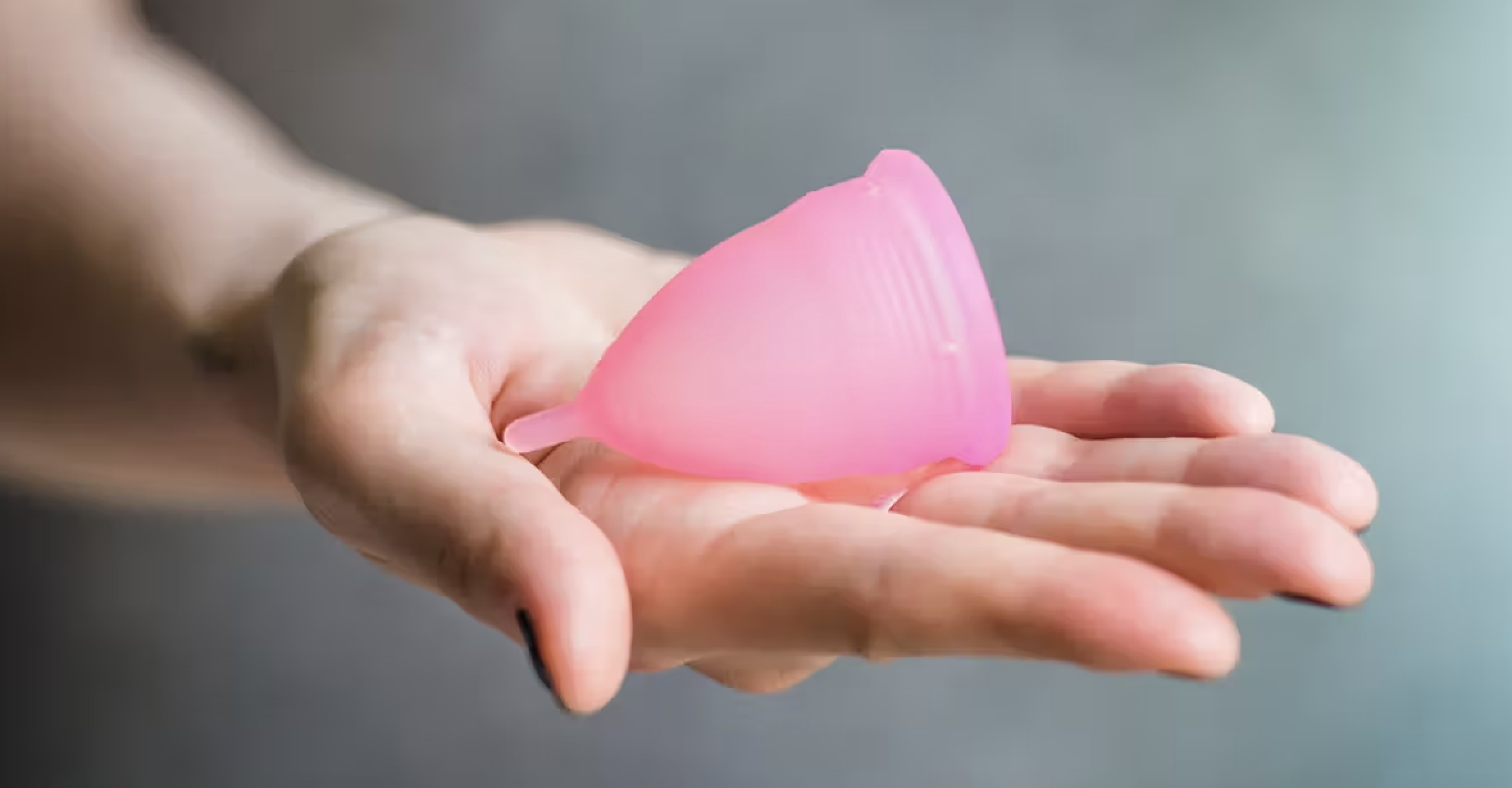A menstrual cup resting on an open palm, showing its real size